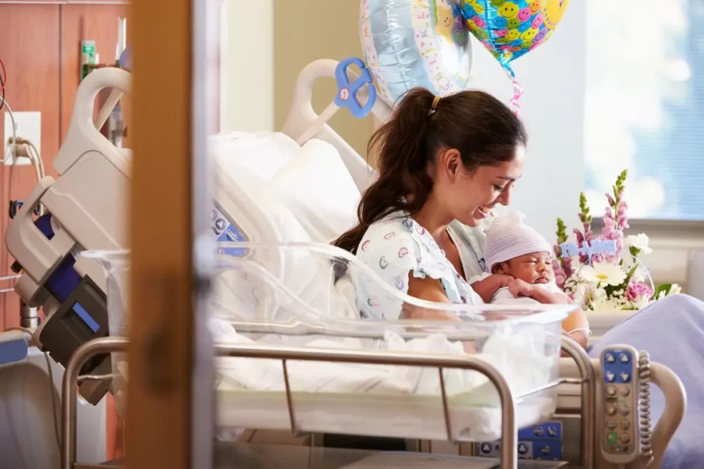 Mutter mit Baby im Krankenbett - Glückwünsche zur Geburt für die Mutter