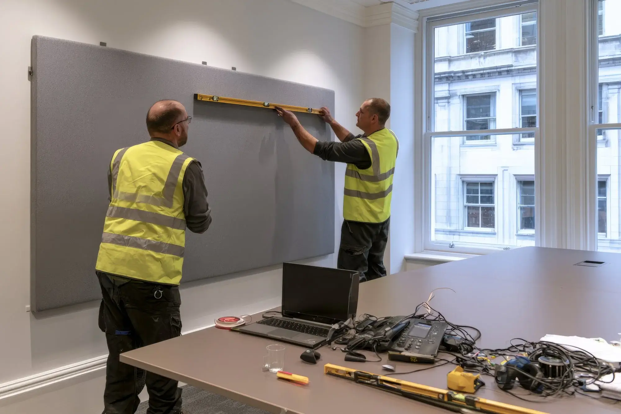 office-workers-installing-fabric-acoustic-panel-with-level-tool-meeting-room_108855-12214